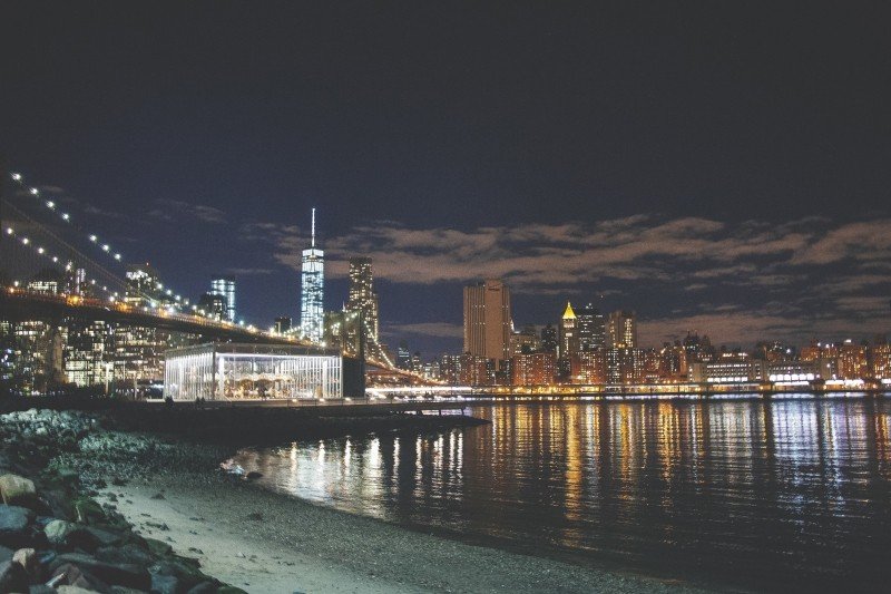 New York City lights reflected across the waterfront at night